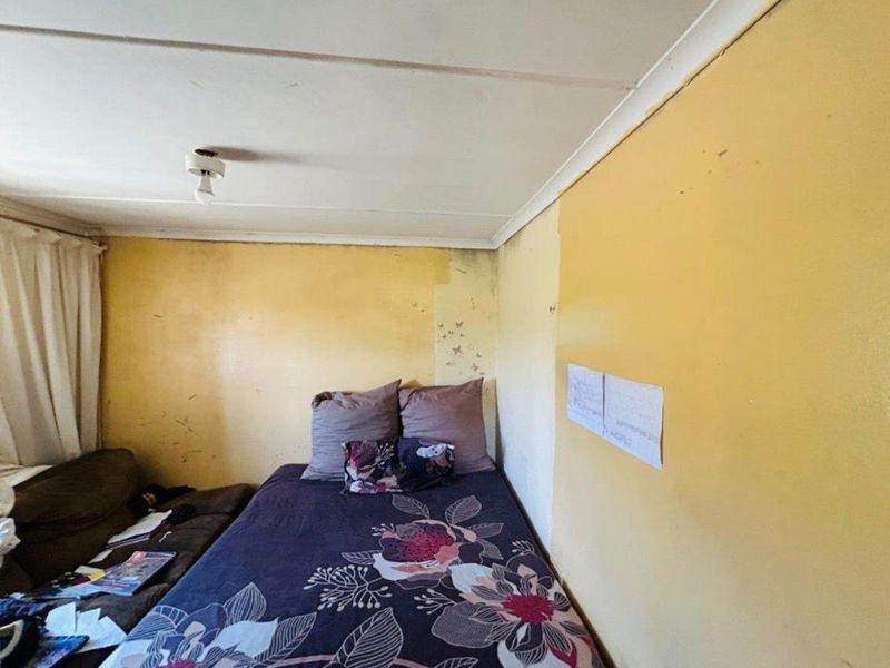 A bedroom space requiring cosmetic updates, featuring visible wall surface wear and dated finishes, offering potential for renovation and modernization.