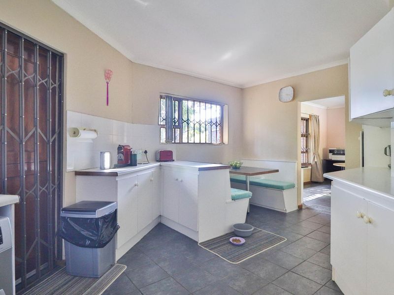 A functional kitchen featuring built-in cabinetry, tiled flooring, and a built-in breakfast nook, with direct access to adjacent living areas.