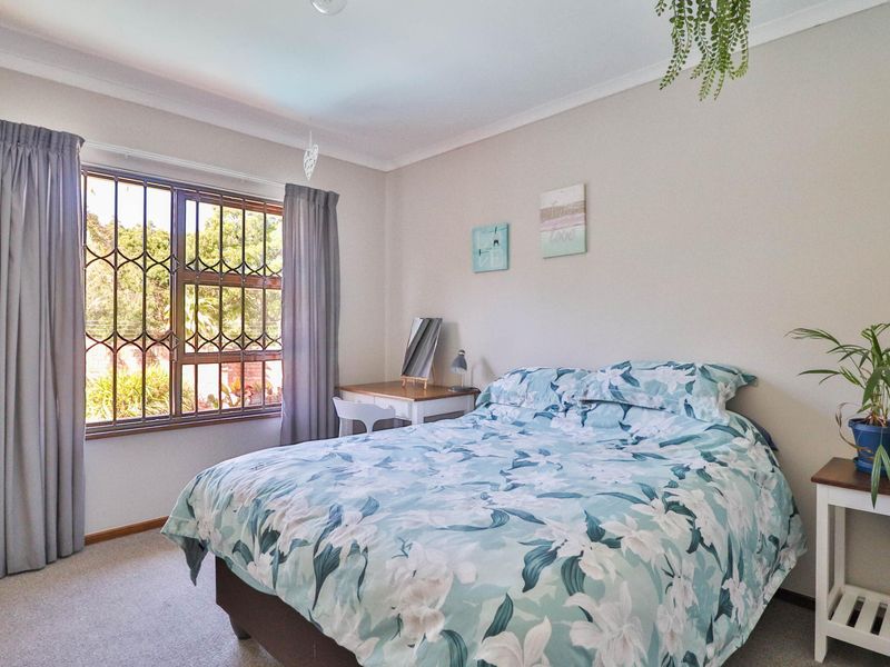 A well-lit bedroom featuring carpeted flooring, coved ceilings, and a window fitted with security bars.