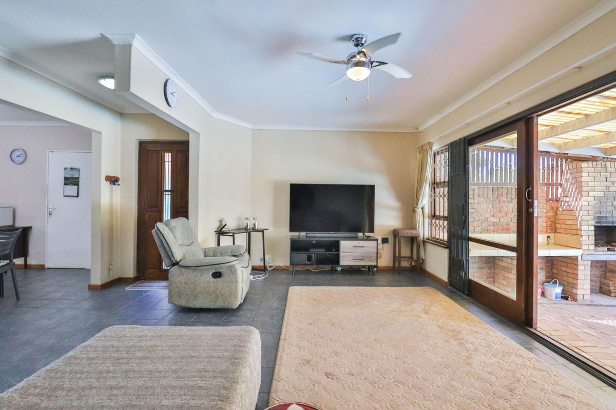 Spacious living room featuring tiled flooring, a ceiling fan, and large sliding glass doors providing direct access to the outdoor patio area.