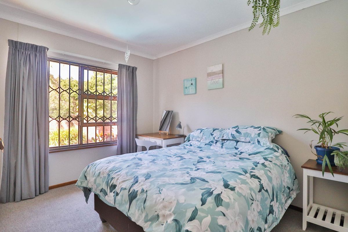 A well-lit bedroom featuring carpeted flooring, coved ceilings, and a window fitted with security bars.
