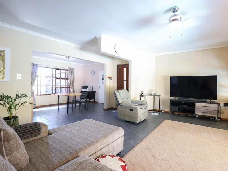 Spacious open-plan living and dining area featuring tiled flooring, neutral walls, and a ceiling fan, providing a versatile layout for family living.