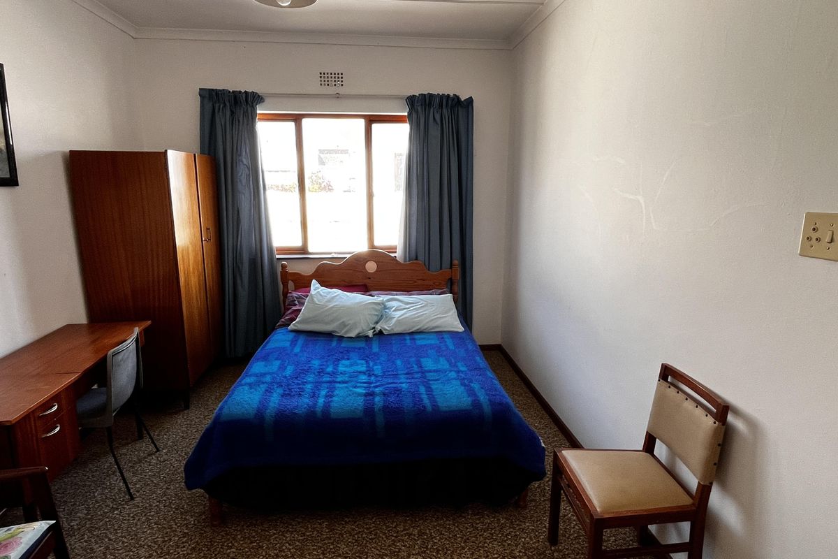 A functional bedroom featuring carpet flooring and a window with natural light, offering a blank canvas for potential cosmetic updates and modernization.