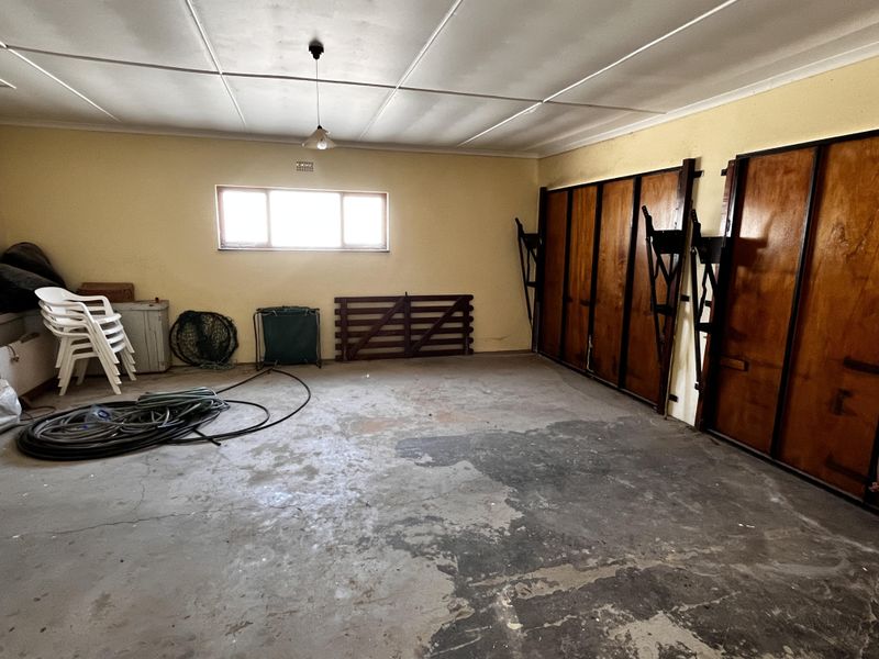 A spacious garage featuring a concrete floor, timber wall paneling, and a functional window, offering ample storage or workspace potential.