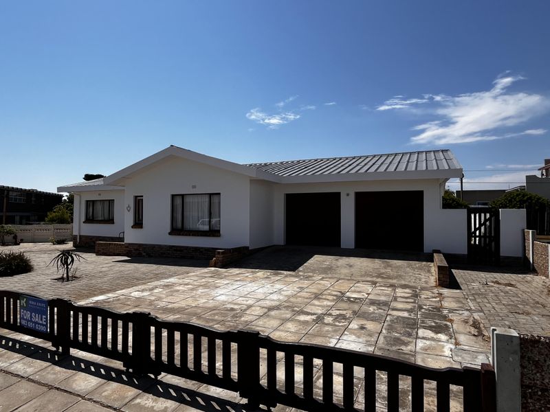Front view of a single-story house featuring a double garage, paved driveway, and a clean white exterior finish.