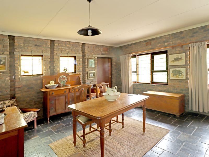 Dining room featuring rustic exposed brick walls, slate tile flooring, and natural light through steel-framed windows with security bars.