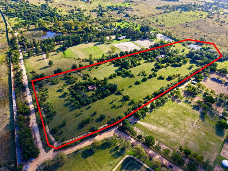 Aerial view of a large farm property featuring expansive green paddocks, mature trees, and established boundary fencing.