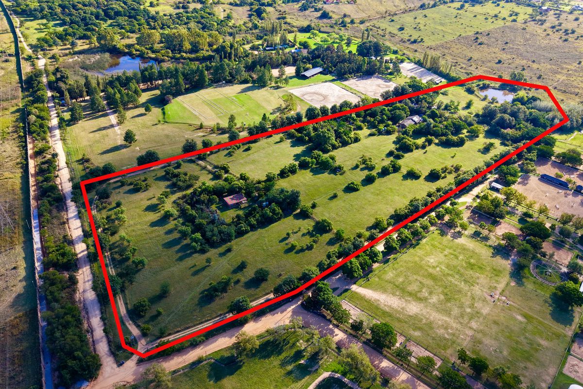 Aerial view of a large farm property featuring expansive green paddocks, mature trees, and established boundary fencing.