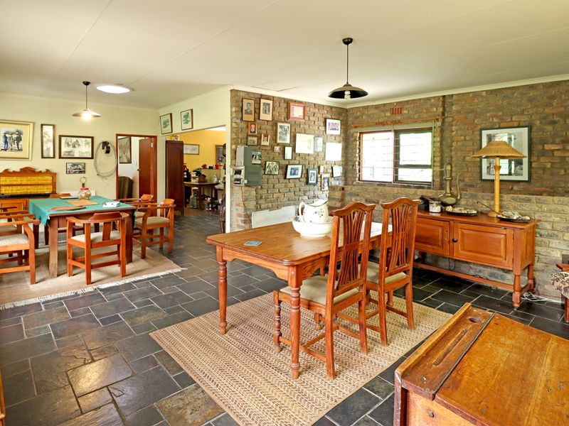 Spacious dining area featuring rustic exposed brick walls, slate tile flooring, and natural light from a skylight, creating a warm and traditional atmosphere.