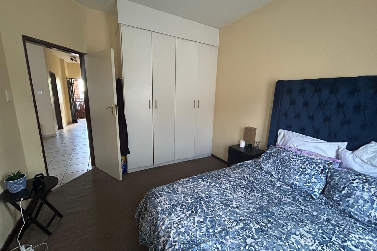 A functional bedroom featuring built-in cupboards and carpeted flooring, with direct access to the hallway.