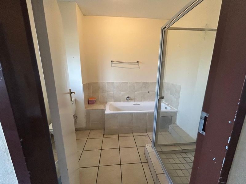A dated bathroom featuring a built-in bathtub, separate shower enclosure, and neutral ceramic tiling throughout.