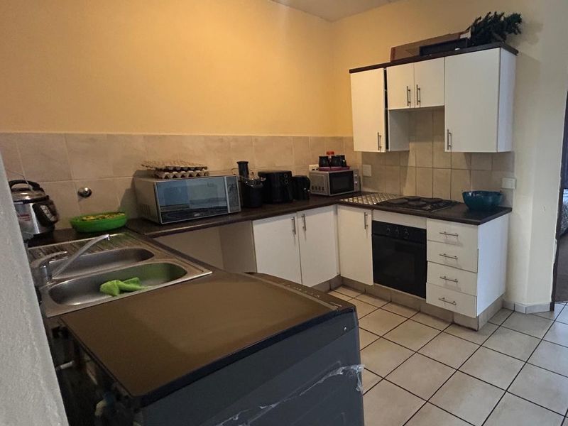 Functional kitchen featuring white cabinetry, tiled backsplash, built-in oven, hob, and double bowl sink with tiled flooring.