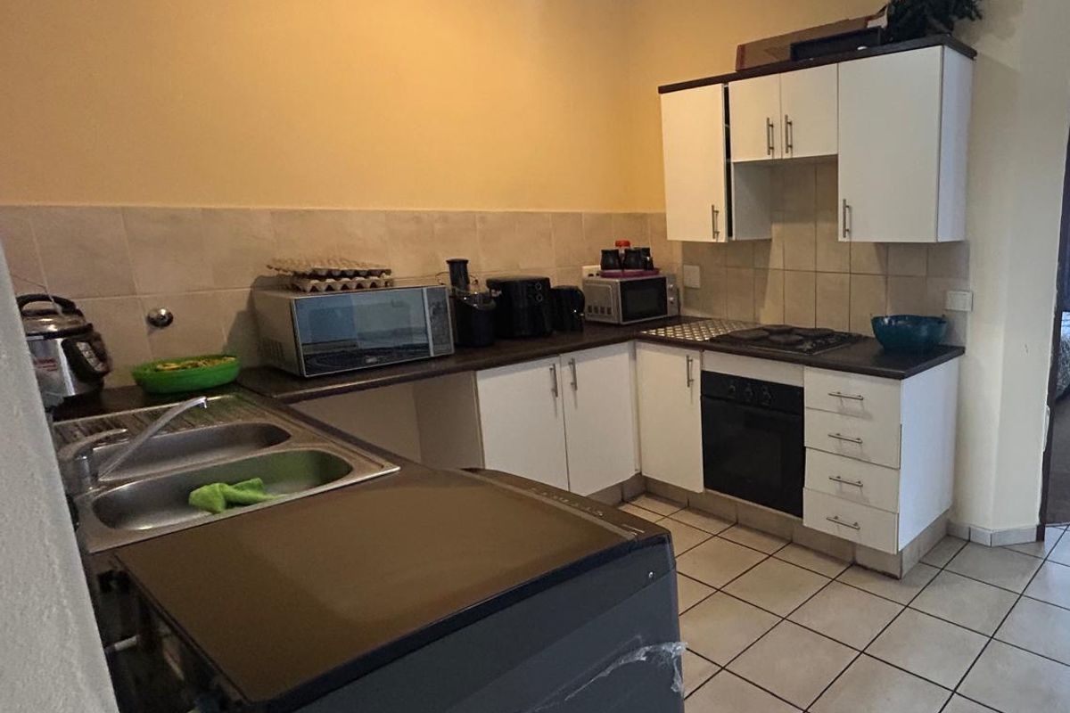 Functional kitchen featuring white cabinetry, tiled backsplash, built-in oven, hob, and double bowl sink with tiled flooring.