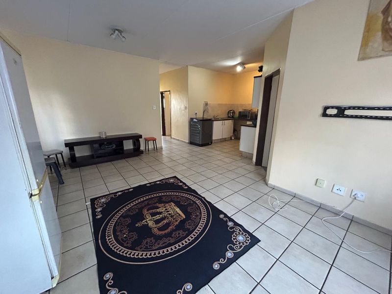 Open plan living area featuring tiled flooring and a functional kitchen space with built-in cabinetry and sink.