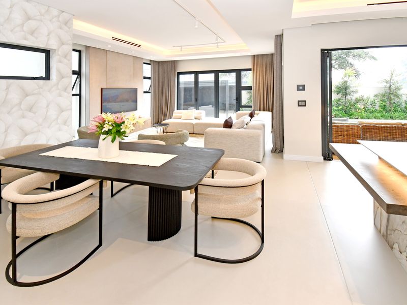 Spacious open-plan living and dining area featuring high-end finishes, recessed lighting, and seamless indoor-outdoor flow through large bi-fold doors.
