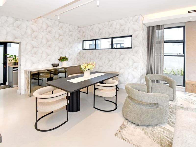 Modern open-plan living and dining area featuring high-end finishes, neutral wallpaper, recessed lighting, and seamless flow to adjacent utility space.