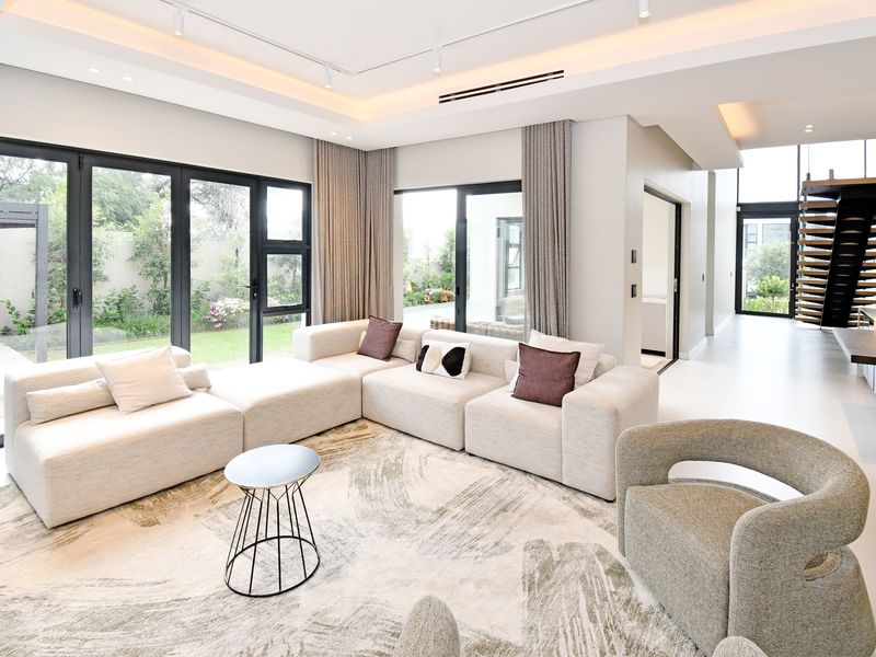 Modern open-plan living area featuring high-end finishes, recessed lighting, ducted air conditioning, and seamless access to the garden through large aluminium sliding doors.