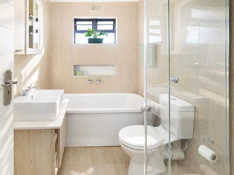 Modern bathroom featuring a built-in bathtub, separate glass-enclosed shower, countertop basin, and neutral tiled finishes throughout.