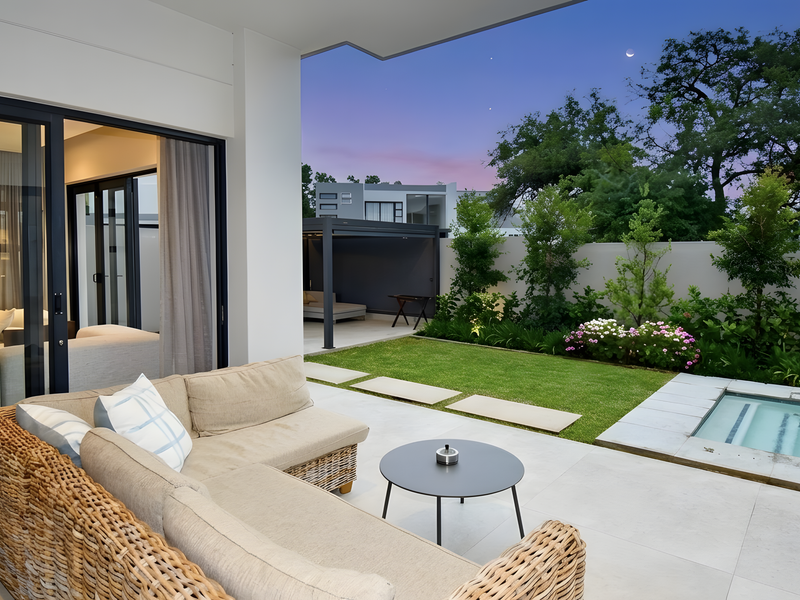 A modern covered patio featuring tiled flooring, seamless indoor-outdoor flow through sliding doors, a private swimming pool, and a well-maintained landscaped garden.