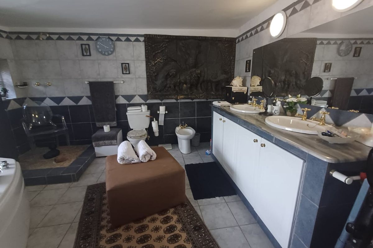 Spacious bathroom featuring a double vanity, bidet, toilet, and decorative wall tiling with a large integrated mirror.