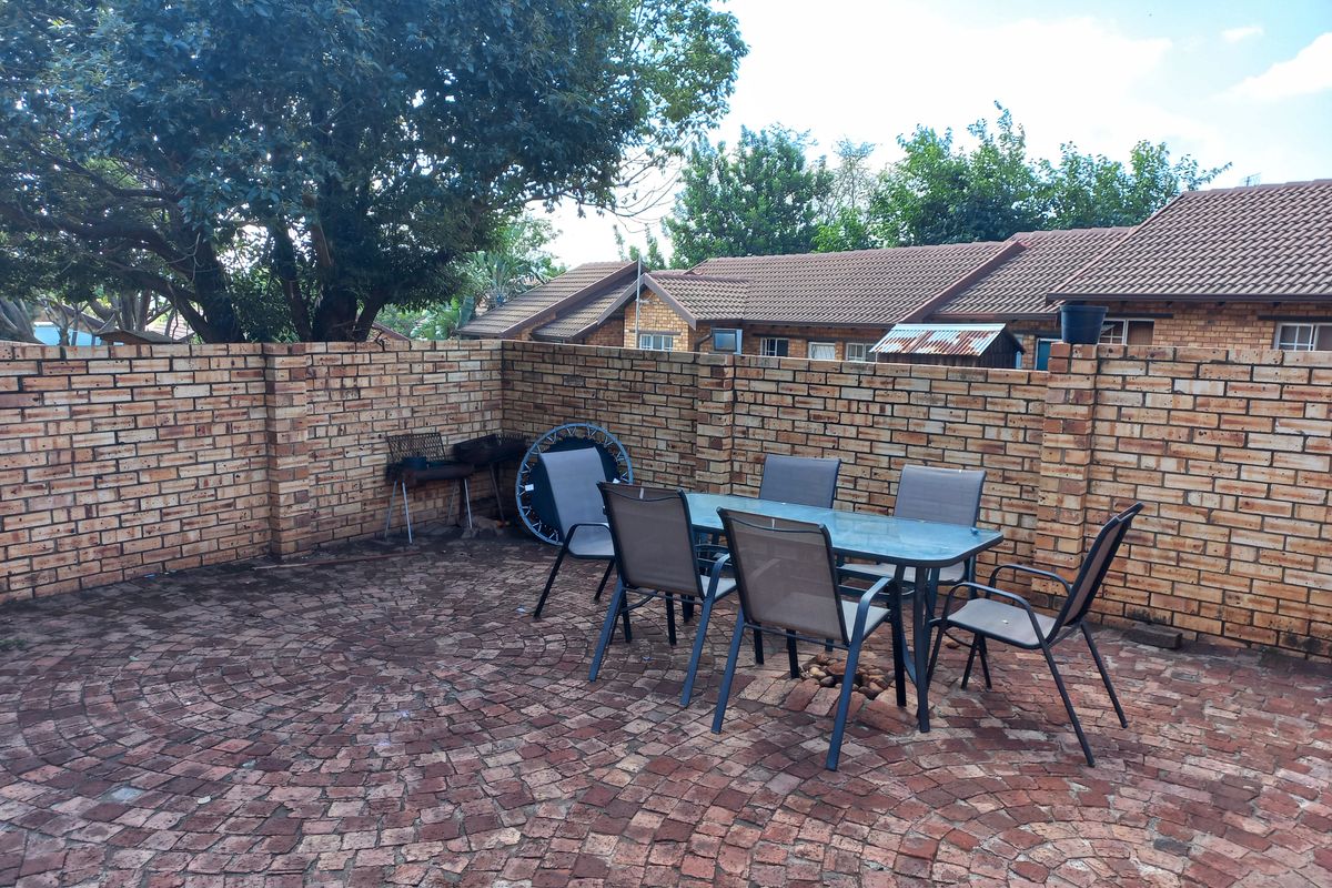 A private rear courtyard featuring a circular brick paved patio enclosed by a sturdy face-brick boundary wall.