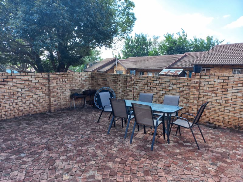A private rear courtyard featuring a circular brick paved patio enclosed by a sturdy face-brick boundary wall.
