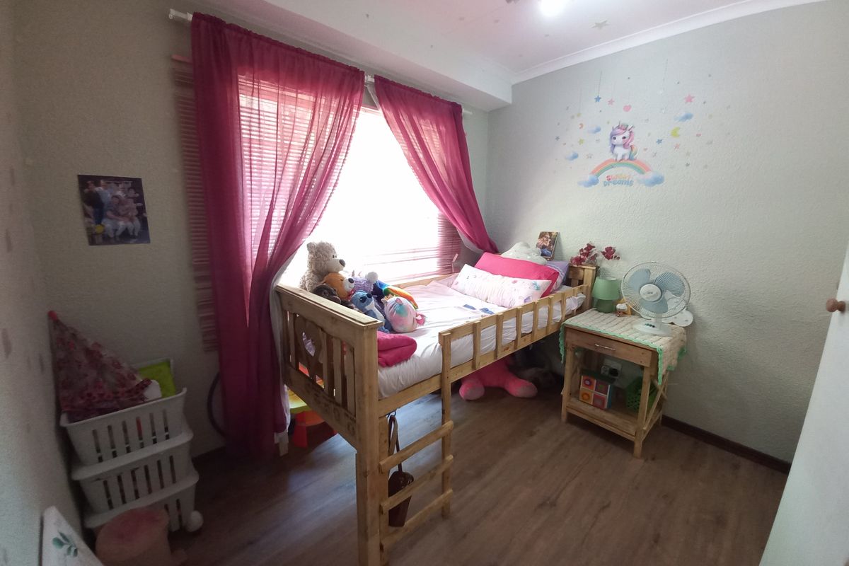 A functional bedroom featuring laminate flooring, coved ceilings, and venetian blinds, providing a comfortable space for rest.