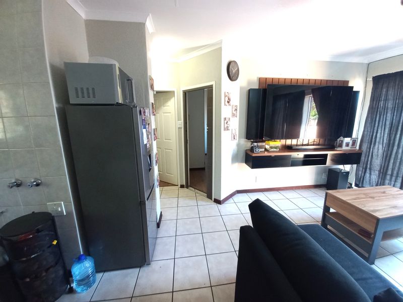 Open plan living area featuring tiled flooring, coved cornicing, and a built-in wall-mounted media console unit.