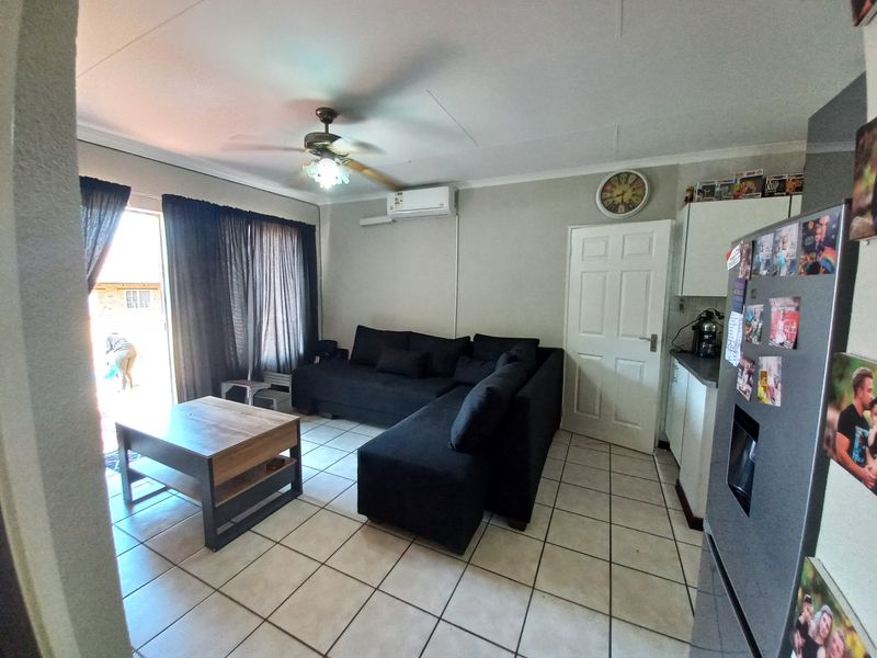 Open-plan living area featuring tiled floors, a ceiling fan, and a split-system air conditioner, with direct access to an outdoor space via sliding doors.