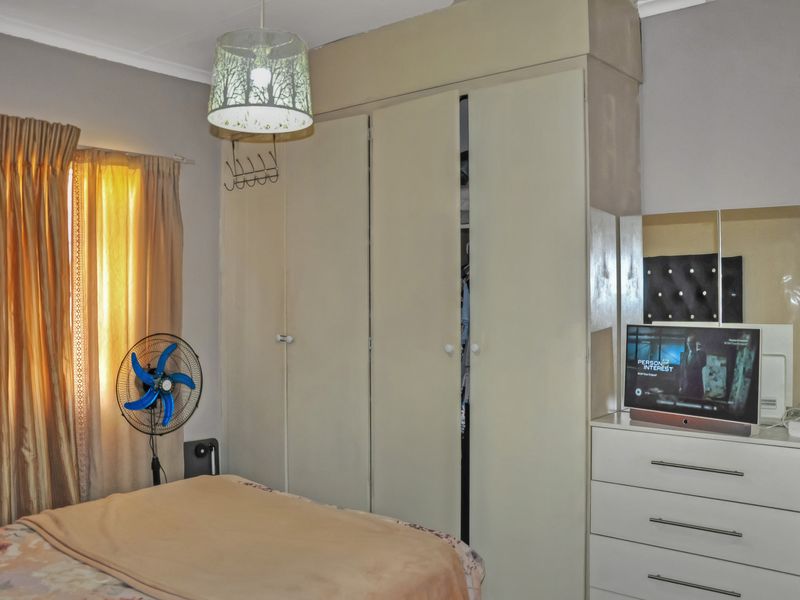 A bedroom featuring a built-in wardrobe with neutral-toned doors and standard ceiling cornice detailing.