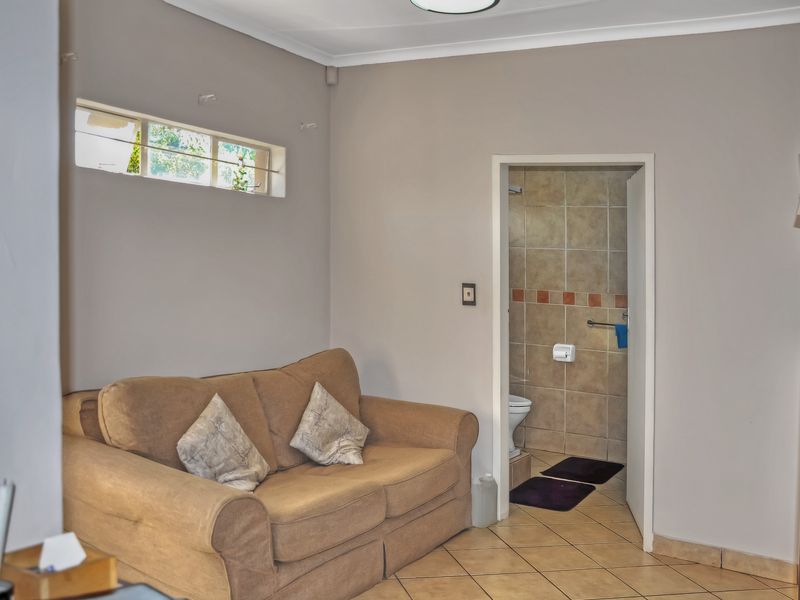 A living area featuring tiled flooring and a high-level window, with direct access to an adjoining bathroom.