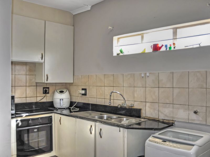 A functional kitchen featuring built-in cabinetry, granite countertops, a stainless steel sink, and integrated oven and hob with tiled backsplash.
