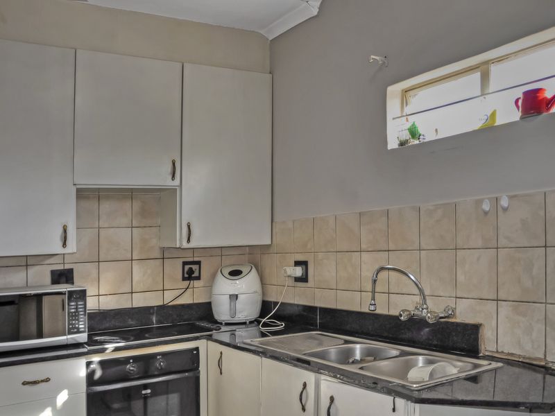 A functional kitchen featuring built-in cabinetry, black granite countertops, a double bowl sink, and integrated oven and hob with tiled backsplash.