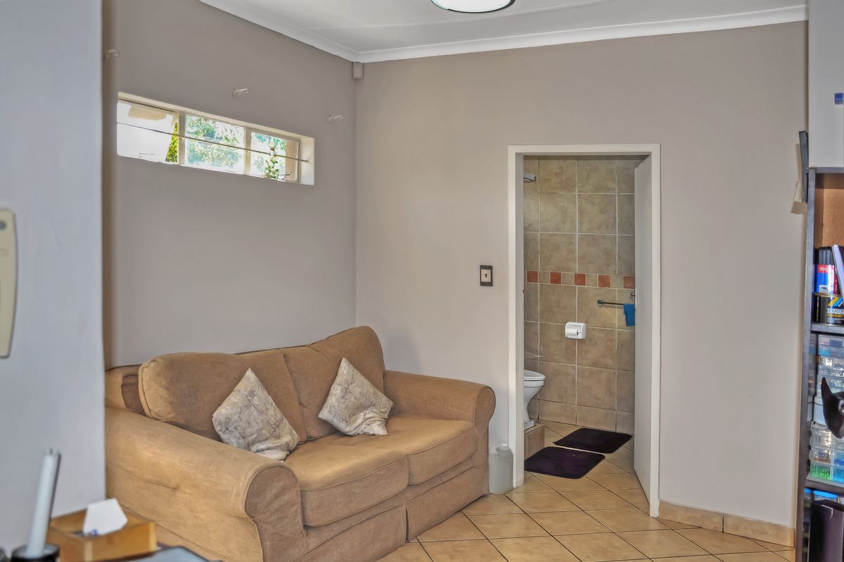 A living area featuring tiled flooring and a high-level window, with direct access to an adjoining bathroom.