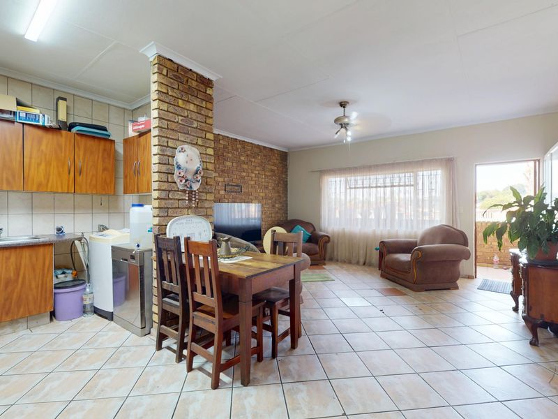 Open-plan living and kitchen area featuring exposed brick accents, tiled flooring, and functional cabinetry, offering a versatile space for dining and relaxation.