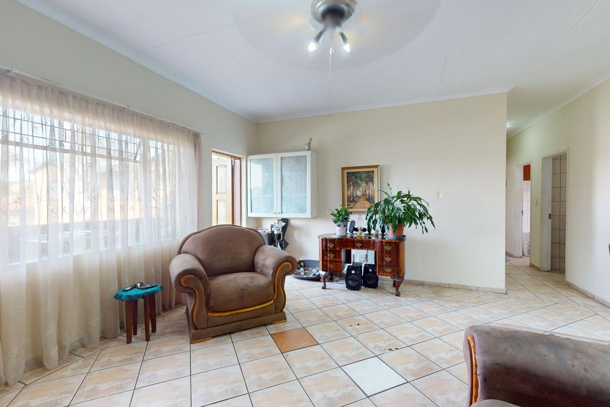 A living room featuring tiled flooring, a ceiling fan, and a built-in wall cabinet, offering a functional space with potential for modernization.