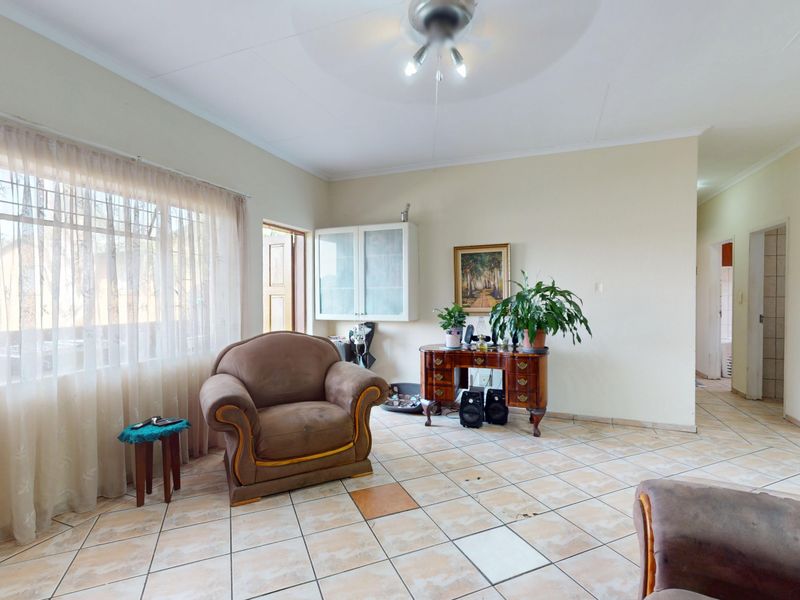 A living room featuring tiled flooring, a ceiling fan, and a built-in wall cabinet, offering a functional space with potential for modernization.