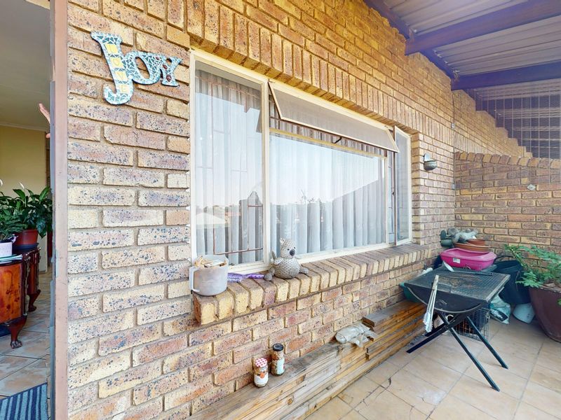 A covered patio area featuring face brick walls and tiled flooring, providing a functional outdoor space adjacent to the main living area.