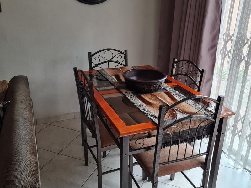 A dining area featuring tiled flooring and a security gate leading to the exterior, providing a functional space for meals.