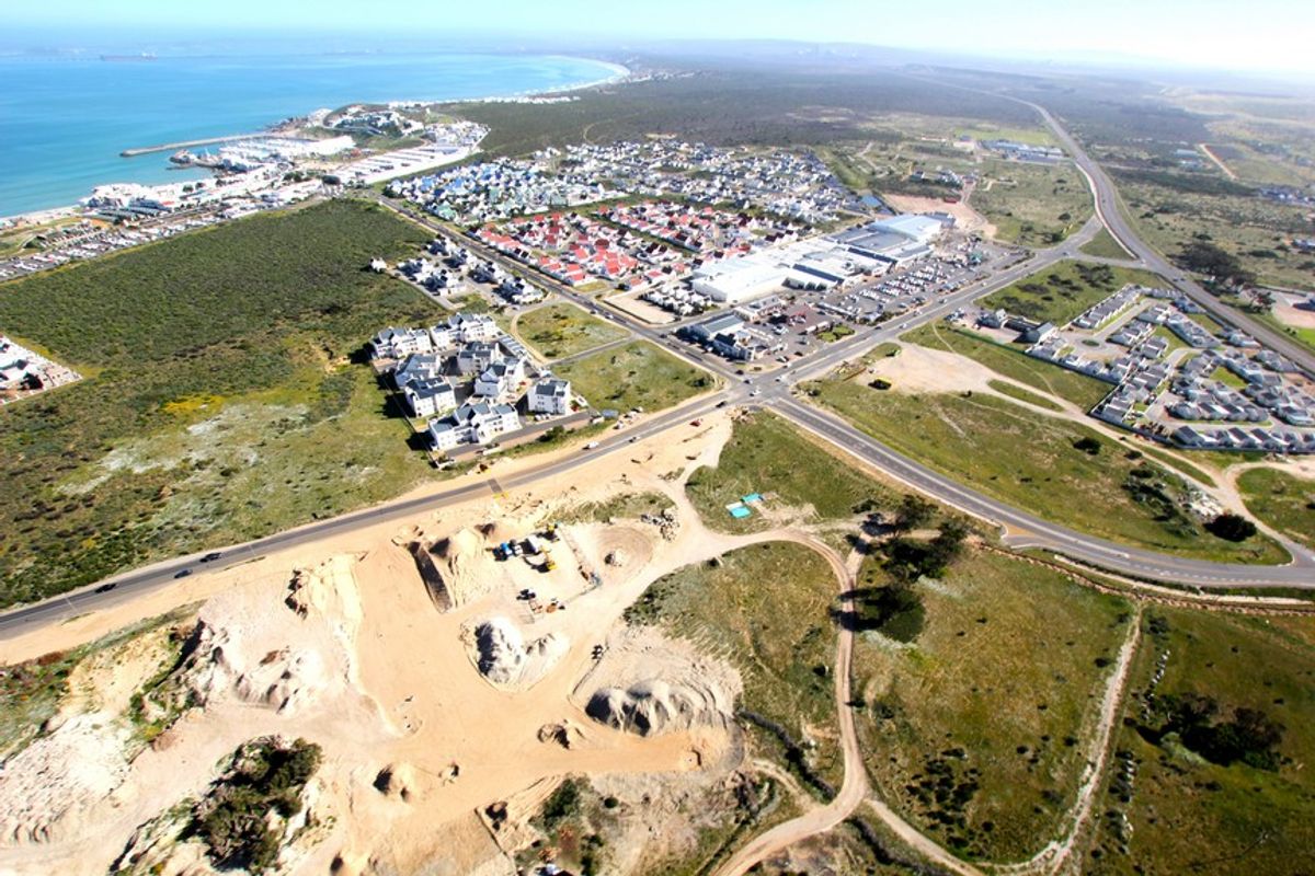 Aerial view of a vacant residential land parcel situated near coastal infrastructure and established suburban developments.