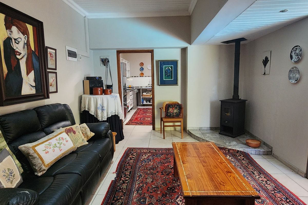 A cozy living room featuring a built-in wood-burning fireplace on a tiled hearth, with direct access to an adjacent kitchen area.