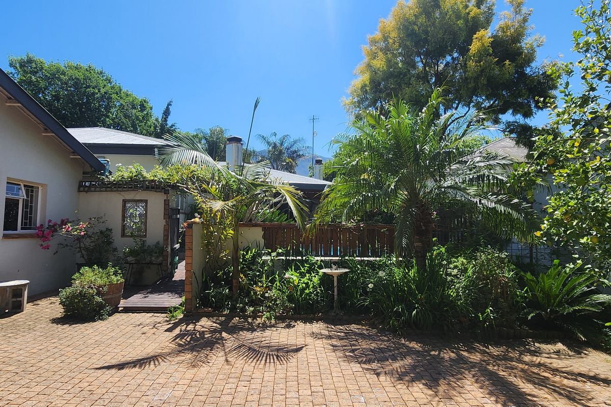 A private rear garden area featuring paved patio space, established landscaping, and a wooden pergola structure.