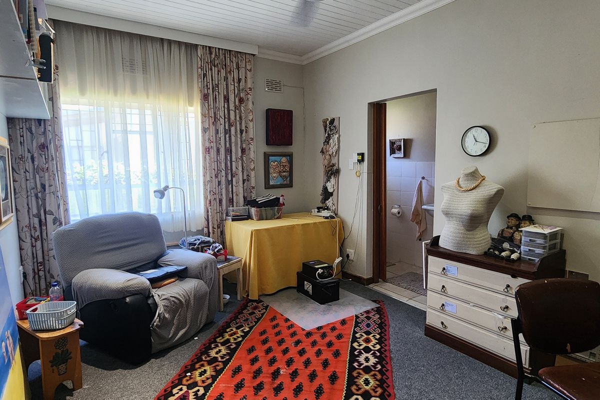 A bedroom featuring a window with curtains, a ceiling fan, and an attached en-suite bathroom.