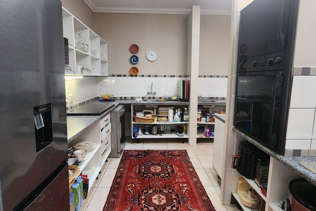A functional kitchen featuring built-in cabinetry, granite countertops, a gas hob, and an integrated oven, offering practical workspace and storage solutions.