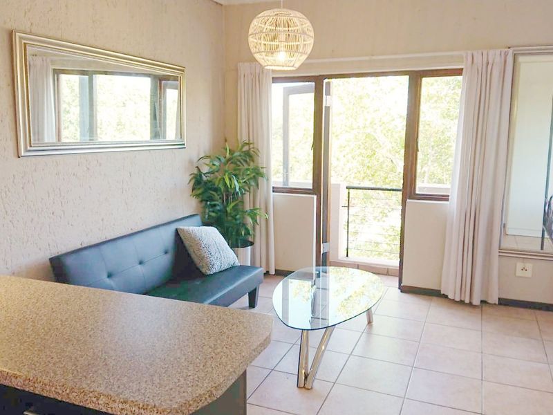 Open plan living area featuring tiled flooring, a breakfast counter, and direct access to a balcony through sliding glass doors.