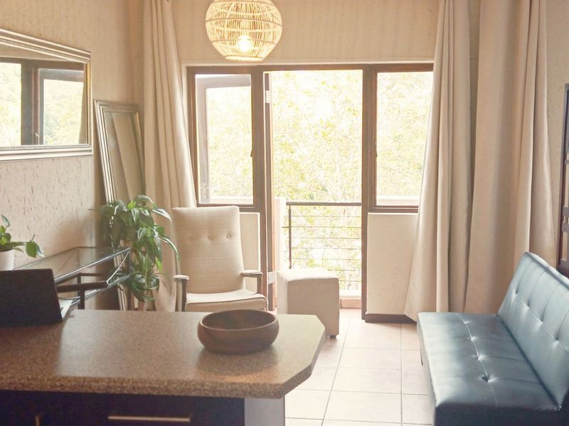 Open plan living area featuring tiled flooring, textured walls, and direct access to a private balcony through sliding glass doors.