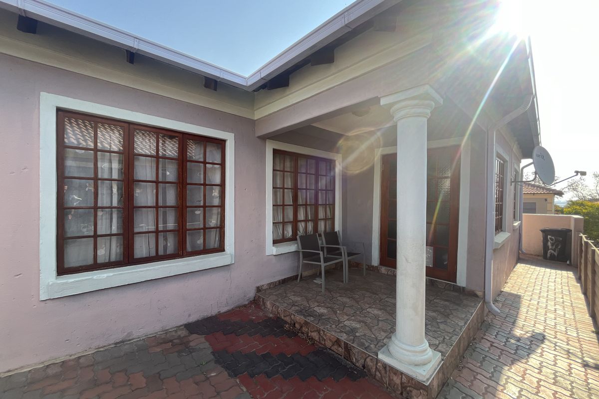 A covered patio area featuring a classical column, timber-framed windows and doors, and paved outdoor flooring, providing a functional transition space.