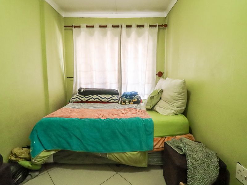 A compact bedroom featuring tiled flooring and a window with a curtain rod, providing a functional space for rest.