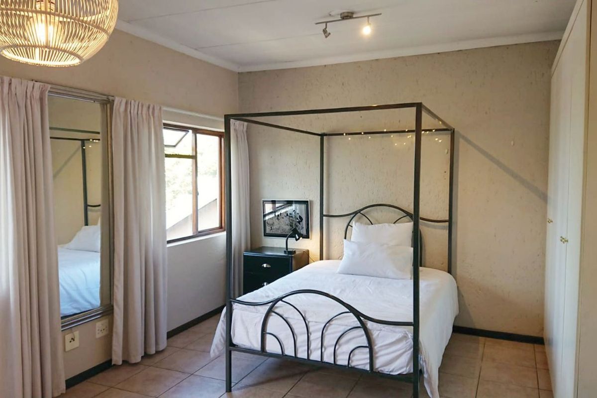 A bedroom featuring tiled flooring, built-in cupboards, and ceiling track lighting, offering a functional space with neutral wall finishes.
