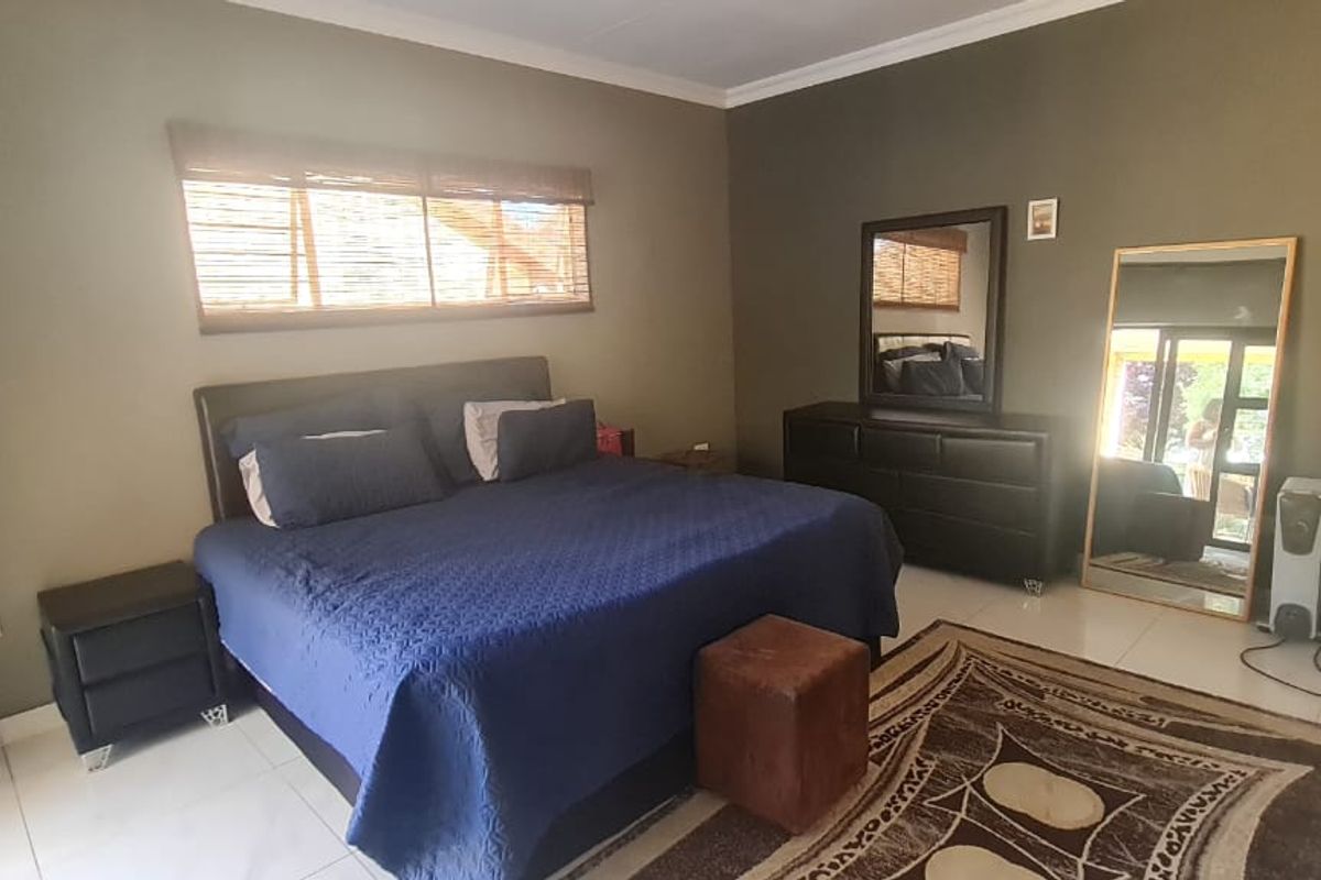 A spacious bedroom featuring neutral wall tones, tiled flooring, and built-in cupboards, offering a functional and comfortable living space.